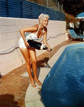 American Actress Jayne Mansfield with a bottle of champagne, near a swimming pool