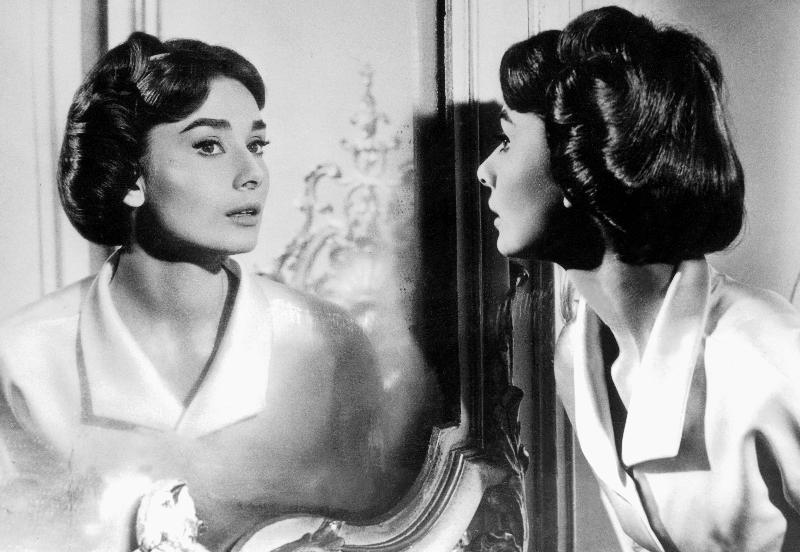 Actress Audrey Hepburn looking at her reflection in the mirror from 