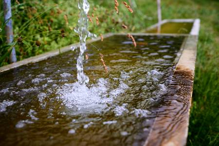 Frisches sprudelndes Wasser in einem kleinen Holzbrunnen auf der Alm 