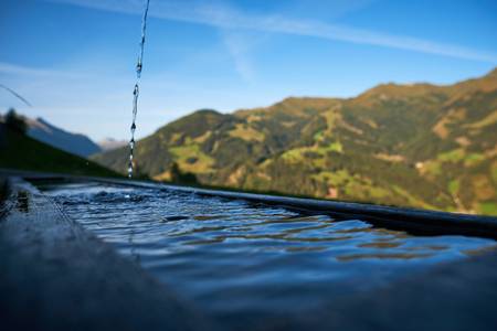 Holzbrunnen auf der Alm mit frischem sprudelndem Quellwasser, Aufnahmen aus dem Bregenzerwald.